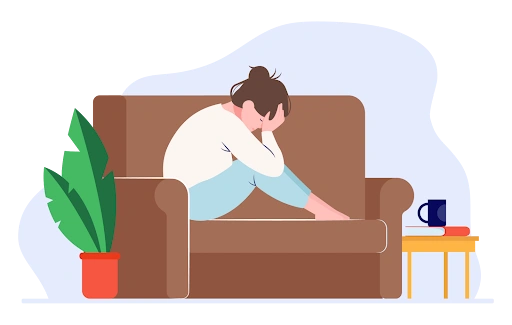 a woman sitting alone on a couch with her head down looking distressed